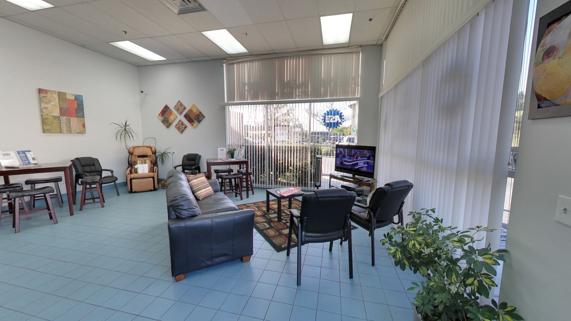 Comfortable waiting room at Laguna Viejo Auto Service with a massage chair, TV, and seating